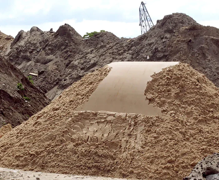 Erdarbeiten auf einer Baustelle: Große Sandhaufen und Erdberge mit dem Schriftzug