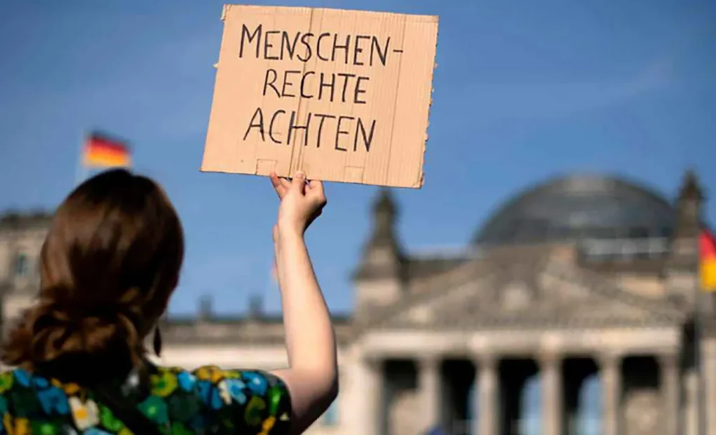Protestierende Person mit Schild "Menschenrechte achten" vor dem Bundestag