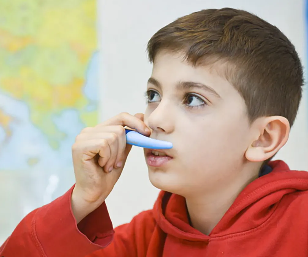 Junger Junge in rotem Hoodie mit Stift an der Lippe, nachdenklich.