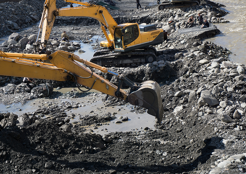 Zwei gelbe Bagger bei Erdarbeiten auf einer schlammigen Baustelle.
