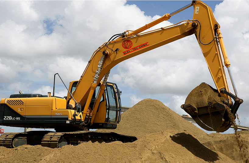Gelber Bagger auf einer Baustelle in Berlin, hebt Sand für Erdarbeiten.